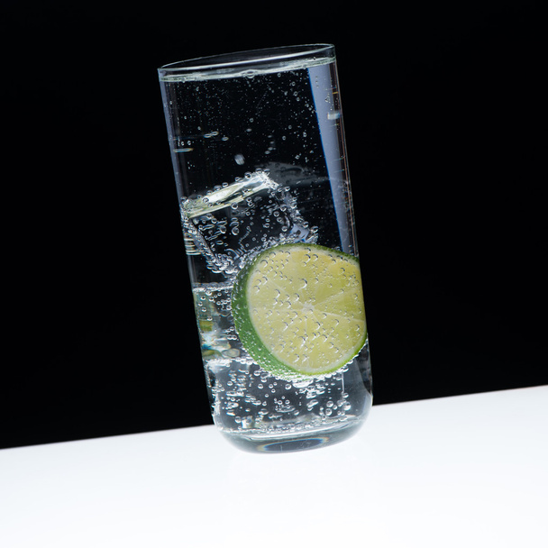 Glass, ice, lemon and indian tonic/close-up with black backgroun - Fotoğraf, Görsel