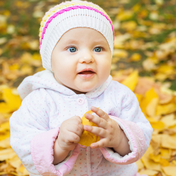 Happy baby outdoor at autumn park playing with yellow leaves - Foto, imagen