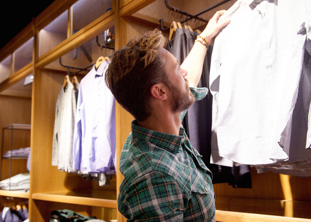 Young man shopping for clothes in store - Foto, Imagem