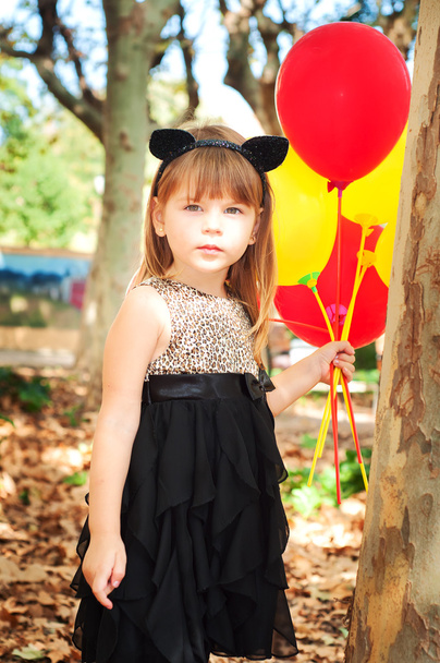 Красива маленька дівчинка, одягнена як кіт з повітряними кулями в руках. Солодка посмішка, ніжний вигляд
 - Фото, зображення