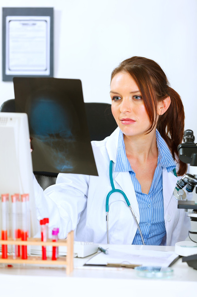 Doctor woman sitting at office table and analyzing patients roen - Foto, Imagem