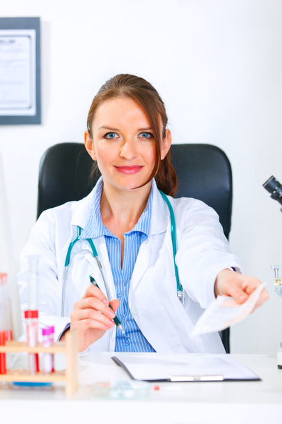 Smiling doctor woman sitting at table and giving medical prescription - Photo, Image