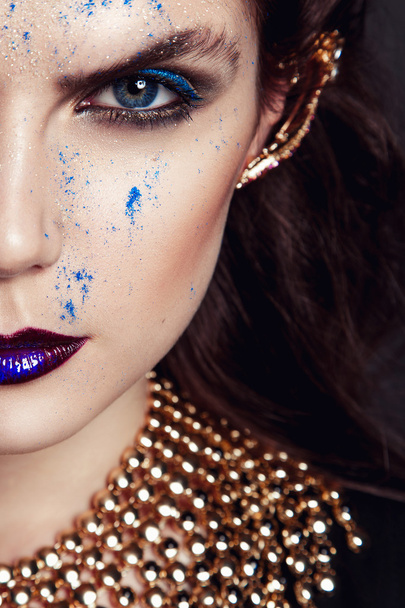 Closeup portrait with deep blue eye, creative makeup and golden accessories - Photo, Image