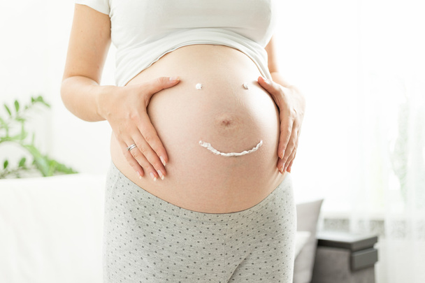 mujer embarazada con sonrisa dibujada por la crema para las estrías en tu
 - Foto, Imagen