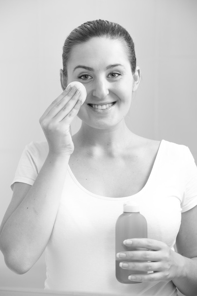 πορτρέτο του όμορφη χαμογελαστή γυναίκα καθαρισμού προσώπου με λοσιόν - Φωτογραφία, εικόνα