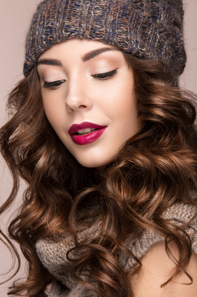 Beautiful girl with gentle makeup, curls in brown knit hat. Warm winter image. Beauty face. - 写真・画像
