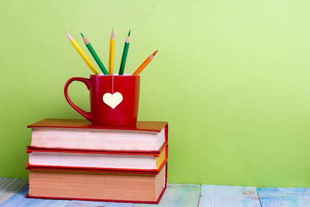 Повернутися до школи. Композиція зі старими старовинними книжками хардбек і червоною чашкою, серцем, олівцями
 - Фото, зображення