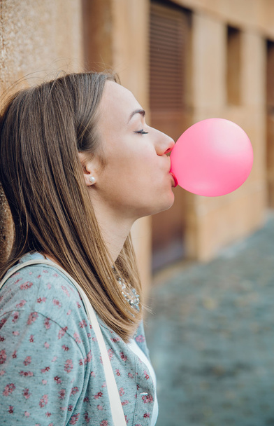 Joven adolescente soplando goma de mascar rosa
 - Foto, imagen