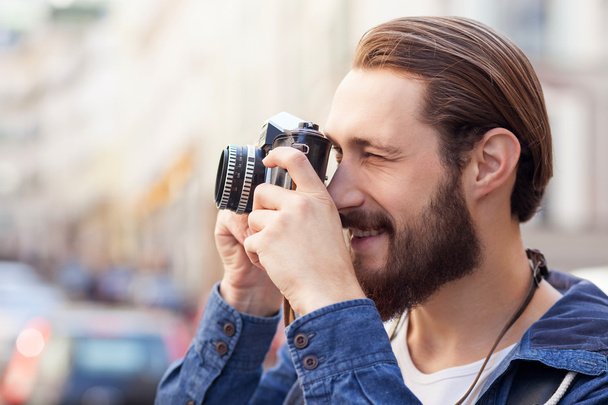 Attractive bearded man is making photos of city - Zdjęcie, obraz