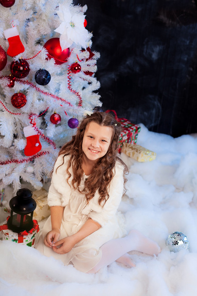 Little girl sitting under the Christmas tree - Fotó, kép
