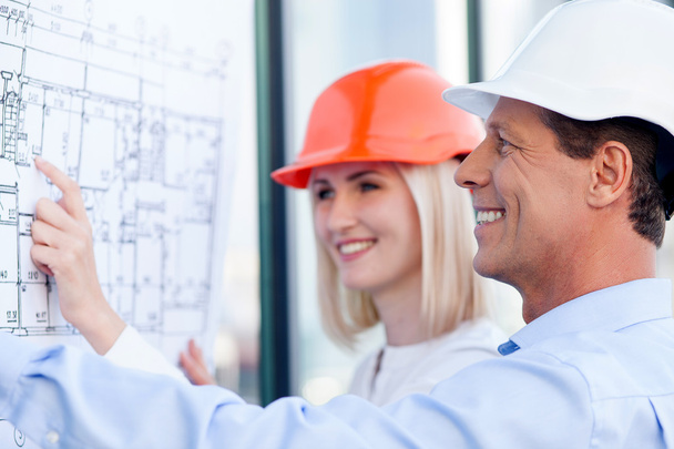Cheerful engineers are discussing plan of building - 写真・画像