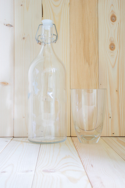 Fles en glas op houten tafel met mornig zon - Foto, afbeelding