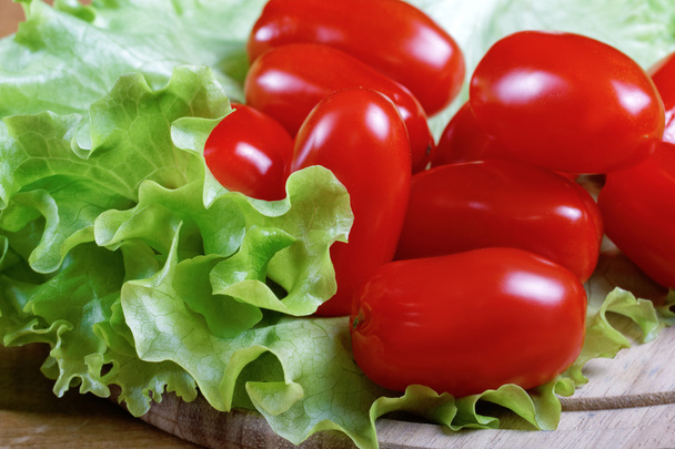 Small tomatoes and salad leaves close up - Foto, afbeelding