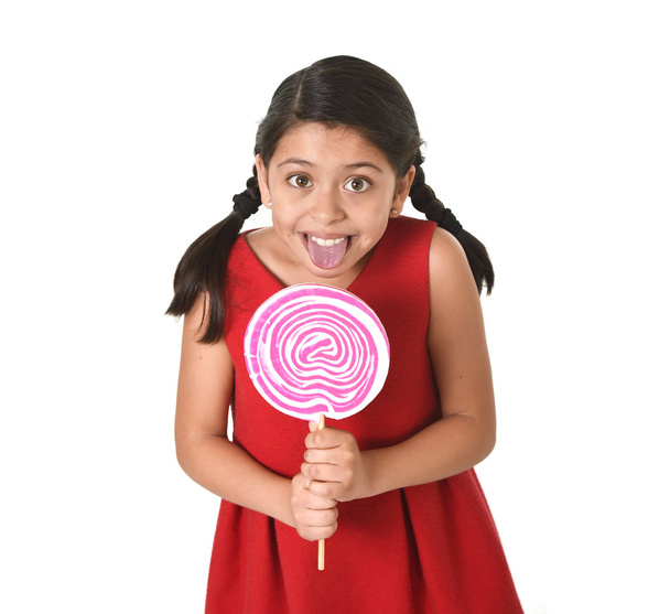 sweet beautiful latin female child holding big pink spiral lollipop candy - Photo, Image