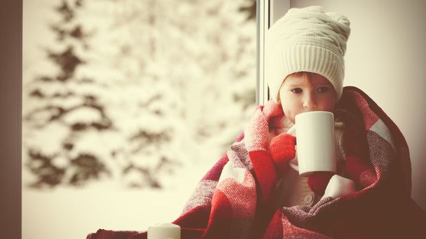 niña pequeña con taza de té caliente en la ventana y mirando
 - Foto, imagen