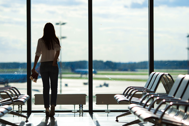Genç kadının yanına uçuş uçak için bekleyen bir Havaalanı lounge penceresinde - Fotoğraf, Görsel