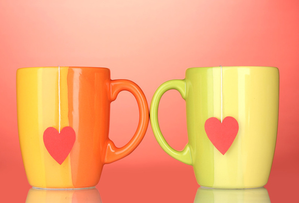 Two cups and tea bags with red heart-shaped label on red background - Φωτογραφία, εικόνα