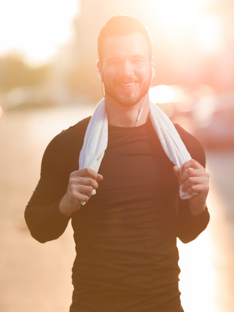 Handsome sporty man  with towel, tired runner resting after even - 写真・画像