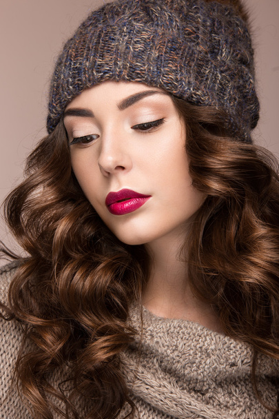 Beautiful girl with gentle makeup, curls in brown knit hat. Warm winter image. Beauty face. - Фото, изображение