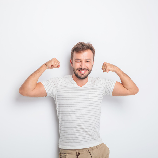 laughing young fit casual man flexing his muscles - Photo, Image