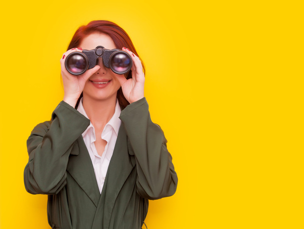 woman with binocular on yellow background - Photo, Image