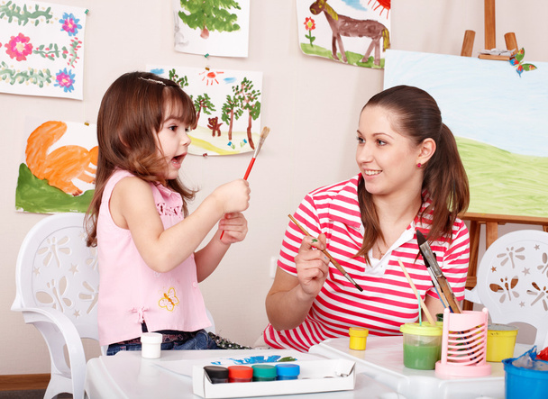 klein meisje schilderen met leraar in de kleuterschool. - Foto, afbeelding