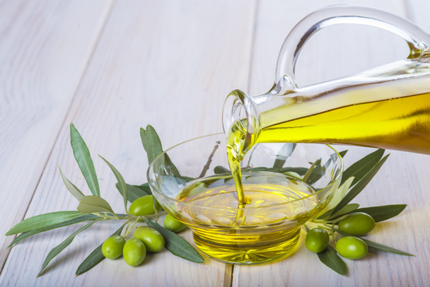 Flasche, die natives Olivenöl extra in eine Schüssel gießt - Foto, Bild