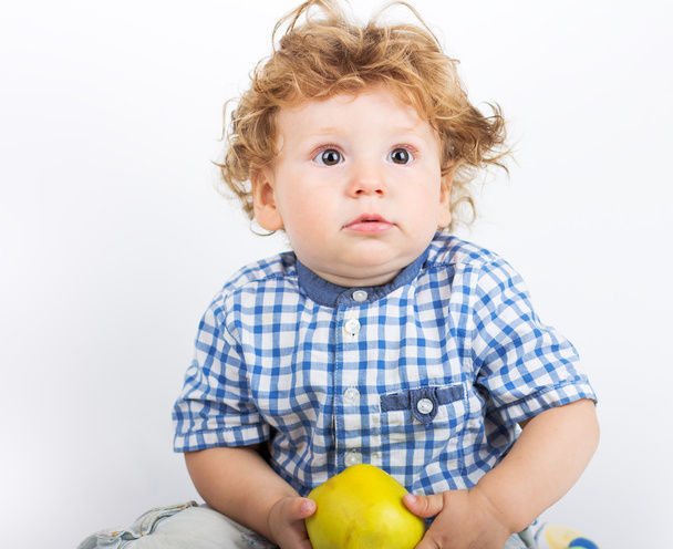 Маленький мальчик держит зеленое яблоко на белом фоне
 - Фото, изображение