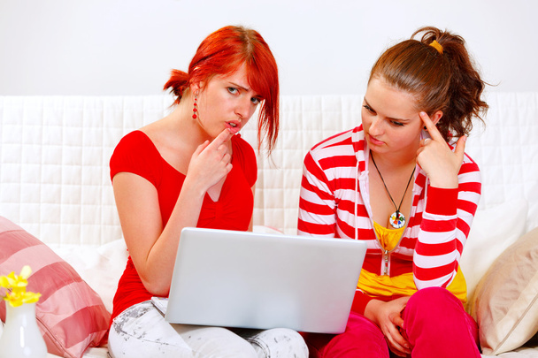 Bewildered girlfriends looking in laptops screen - 写真・画像