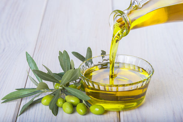 Flasche, die natives Olivenöl extra in eine Schüssel gießt - Foto, Bild