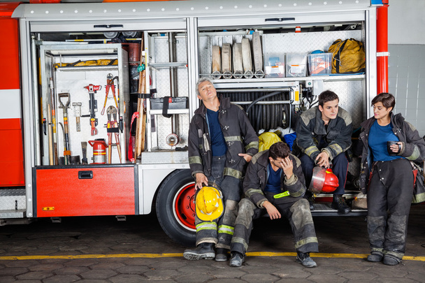 Team Of Exhausted Firefighters At Station - Foto, Bild