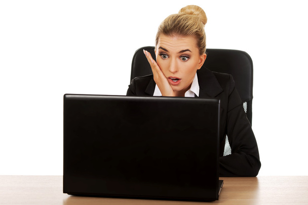 Surprised and curious businesswoman cannot believe what she sees in the laptop screen - Photo, image