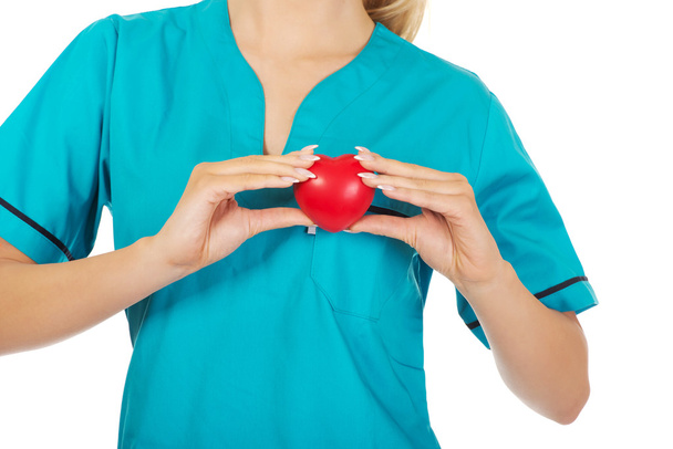 Νοσοκόμα ή γυναίκα γιατρός κρατώντας κόκκινη καρδιά. - Φωτογραφία, εικόνα