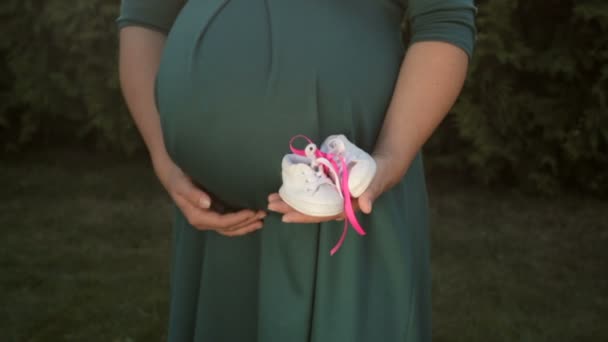 Kép a terhes nő, kis baba cipő a kezében - Felvétel, videó