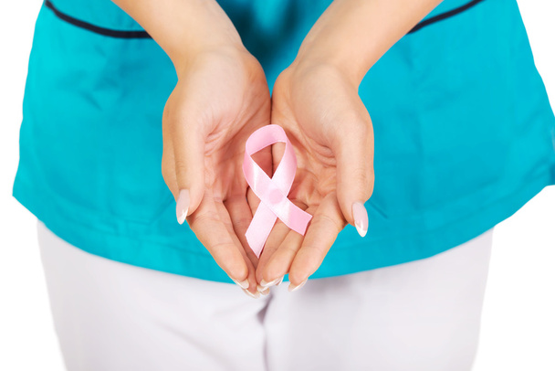 Χαμογελώντας νοσοκόμα κρατώντας ροζ μαστού Καρκίνος ευαισθητοποίηση κορδέλα. - Φωτογραφία, εικόνα