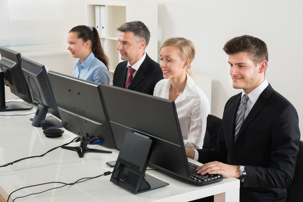 Empresários digitando em computadores desktop
 - Foto, Imagem