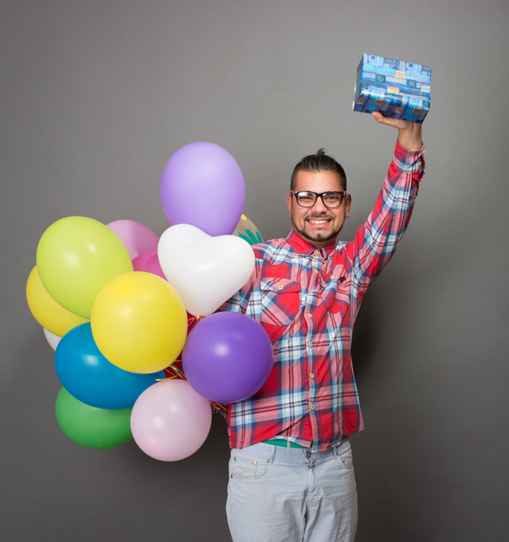 Handsome hipster man with baloons and a present in studio - Valokuva, kuva