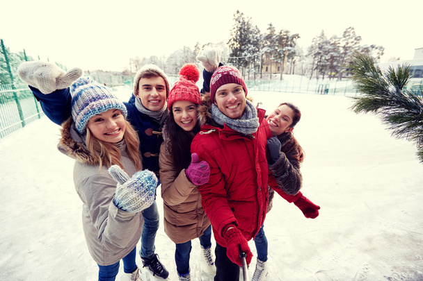happy friends with smartphone on ice skating rink - Фото, изображение