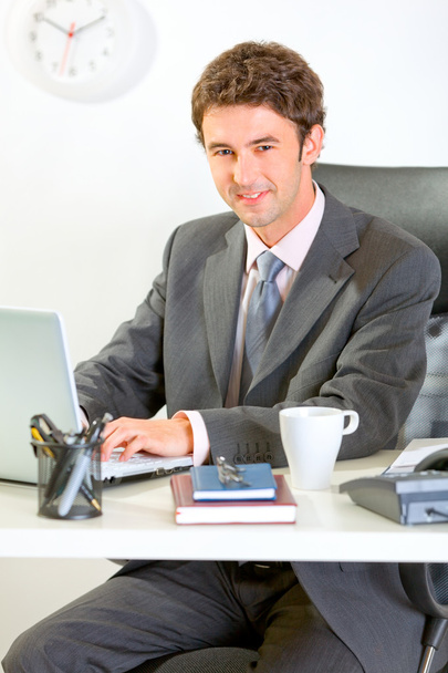 Modern businessman sitting at office desk and working on laptop - Фото, зображення