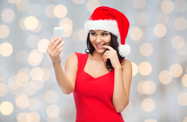 woman in santa hat taking selfie by smartphone - Фото, изображение