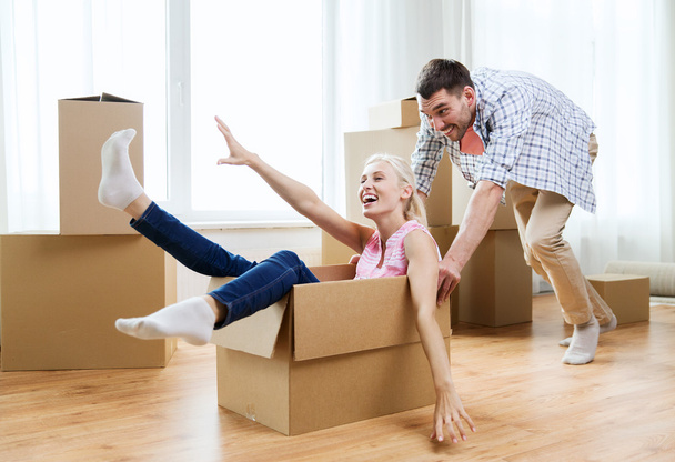 couple with cardboard boxes having fun at new home - Foto, afbeelding