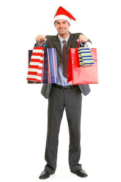 Smiling businessman in Santa hat giving shopping bags - Photo, Image