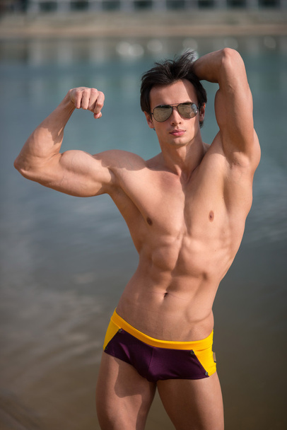 Portrait of a sporty, athletic, muscular sexy man in swimtrunks - Photo, image