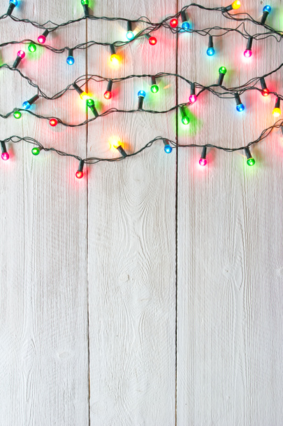 Χριστουγεννιάτικα φώτα πάνω από το λευκό βαμμένο σανίδες για φόντο - Φωτογραφία, εικόνα