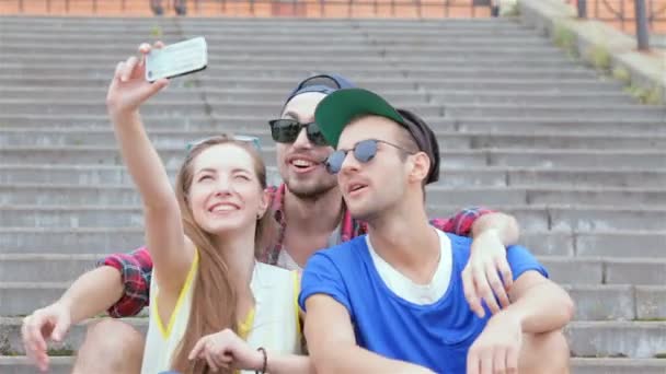 Wesoła dziewczyna siedzi na schodach swoich przyjaciół sprawia, że selfie - Materiał filmowy, wideo