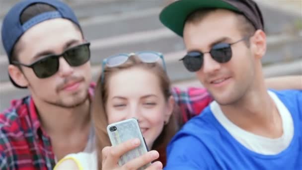 Cheerful girl sitting on the steps of his friends makes selfie - Footage, Video