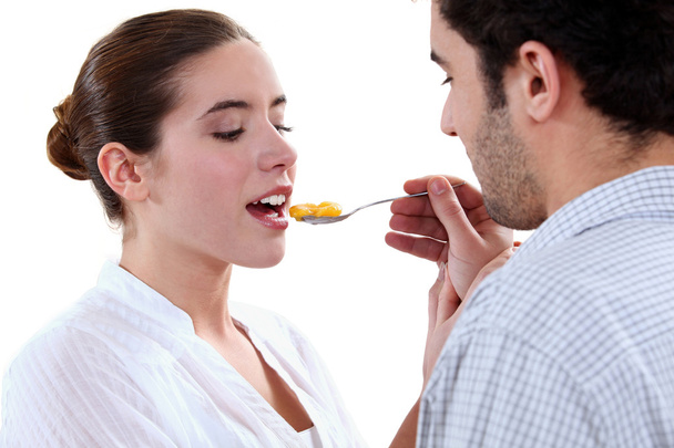 Boyfriend feeding his girlfriend with a spoon - Foto, imagen
