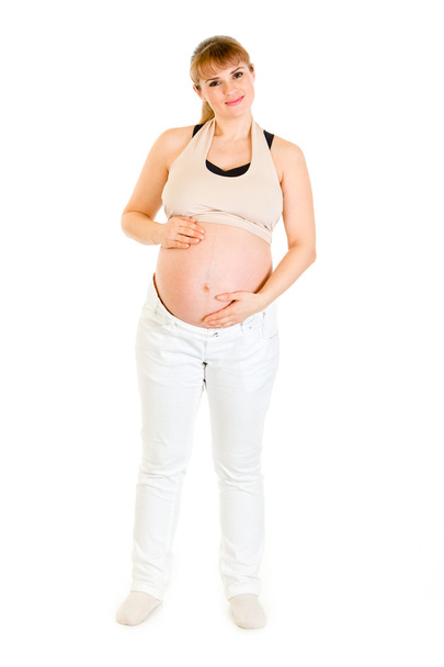 Smiling charming pregnant woman holding her belly isolated on white - Photo, image