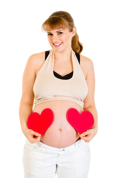 Smiling pregnant woman holding paper hearts near her belly - Photo, Image