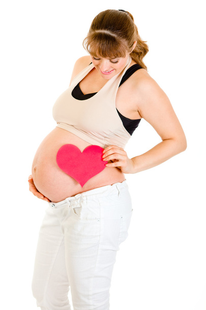 Smiling pregnant woman holding heart near her tummy - Foto, imagen